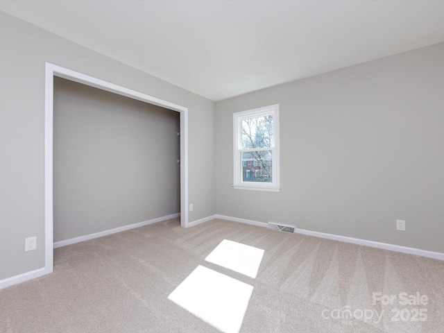 unfurnished bedroom featuring a closet, visible vents, light colored carpet, and baseboards