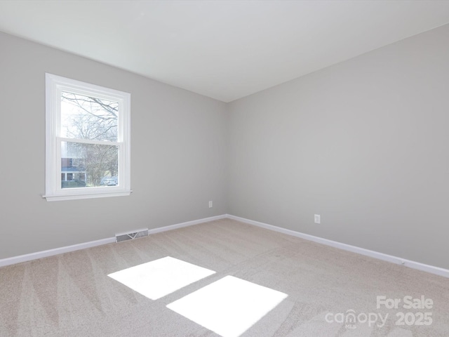 spare room featuring visible vents, baseboards, and light colored carpet