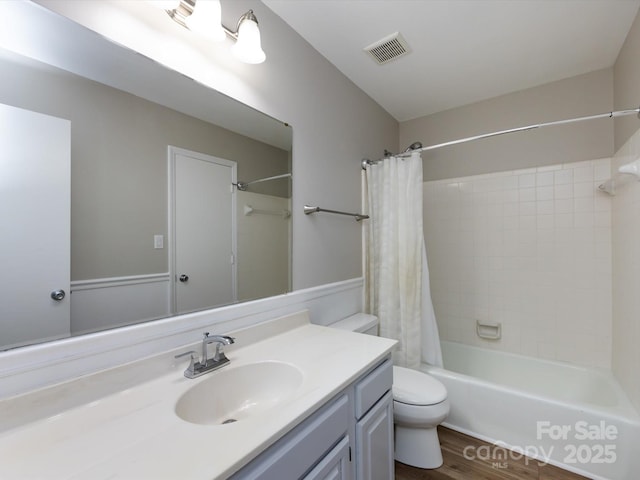 bathroom featuring vanity, wood finished floors, visible vents, shower / bath combination with curtain, and toilet