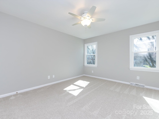 spare room with visible vents, baseboards, light colored carpet, and ceiling fan