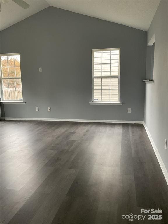 unfurnished room with lofted ceiling, dark wood-style floors, baseboards, and a ceiling fan