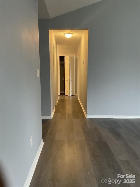 hall with lofted ceiling, dark wood finished floors, and baseboards