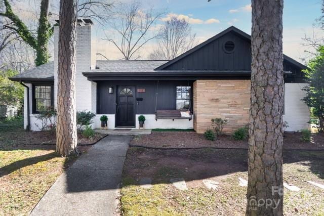 view of front of home featuring a shingled roof, a chimney, and board and batten siding