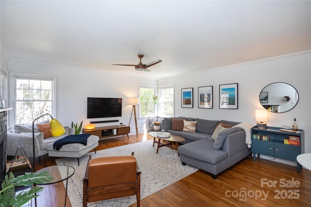 living room with a ceiling fan, ornamental molding, and wood finished floors