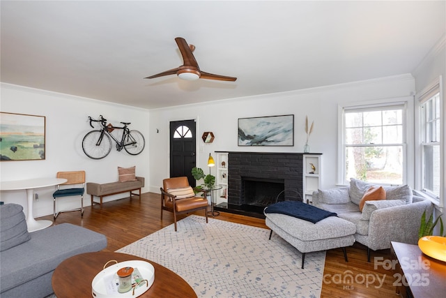 living area featuring ornamental molding, a fireplace, wood finished floors, and a ceiling fan