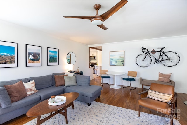 living area with a ceiling fan, crown molding, baseboards, and hardwood / wood-style flooring