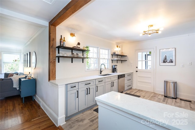 kitchen featuring crown molding, open shelves, stainless steel dishwasher, a sink, and light wood-type flooring