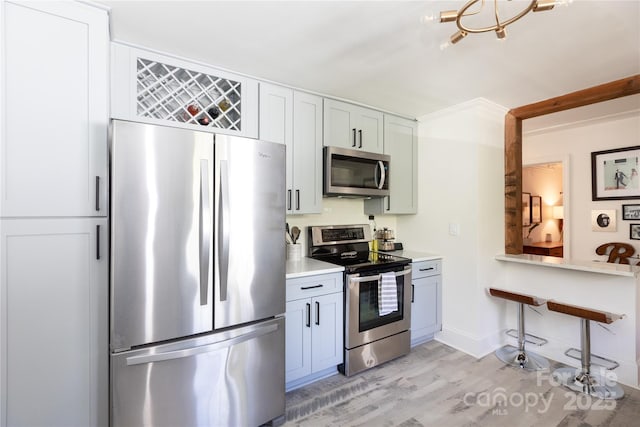 kitchen featuring light wood-style flooring, appliances with stainless steel finishes, light countertops, and baseboards