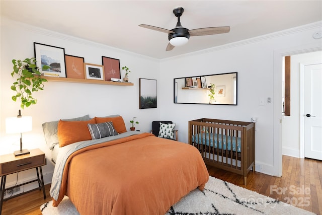 bedroom featuring ornamental molding, wood finished floors, a ceiling fan, and baseboards