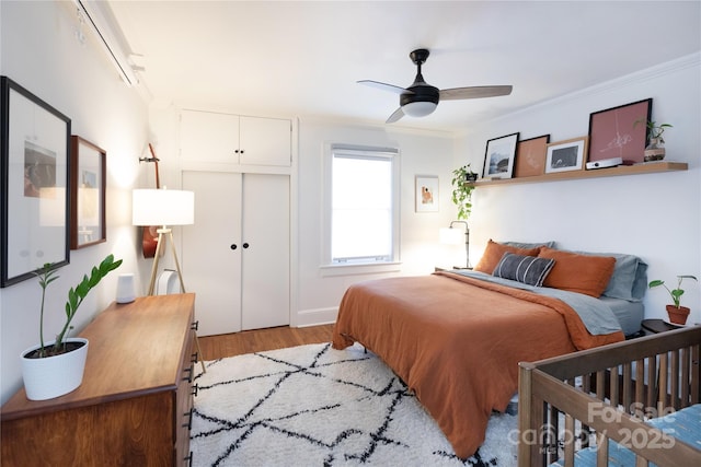 bedroom featuring ornamental molding, a closet, light wood-type flooring, and a ceiling fan