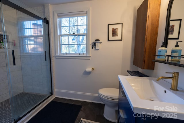 full bathroom with a stall shower, baseboards, vanity, and toilet