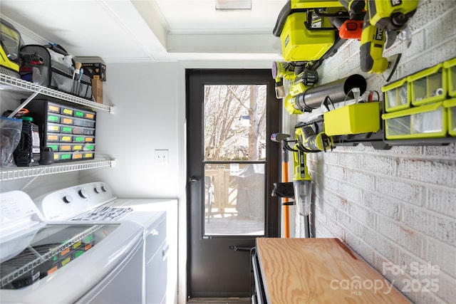 laundry area featuring laundry area, brick wall, and separate washer and dryer