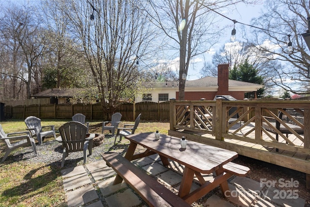 view of patio featuring a fire pit, fence, outdoor dining area, and a wooden deck