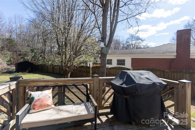 wooden terrace with a fenced backyard and grilling area