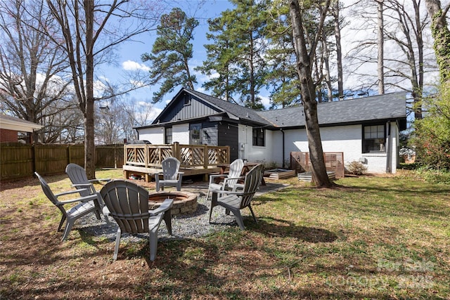 back of property featuring a fire pit, fence, a deck, a yard, and brick siding