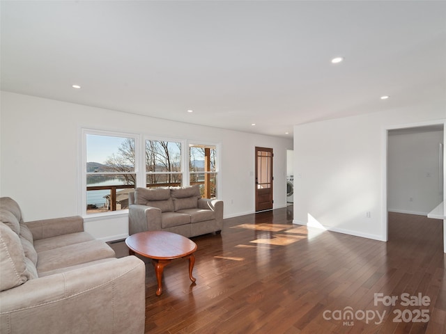 living room featuring dark wood finished floors, recessed lighting, washer / clothes dryer, a water view, and baseboards