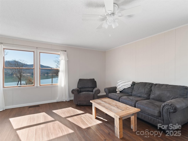 living room with visible vents, ceiling fan, ornamental molding, wood finished floors, and a water view