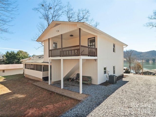 back of property featuring a sunroom, central air condition unit, and a water and mountain view