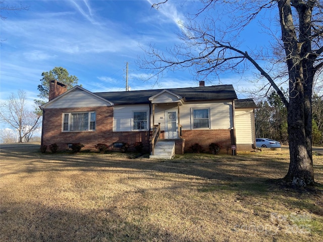 ranch-style house featuring a front yard, brick siding, and a chimney