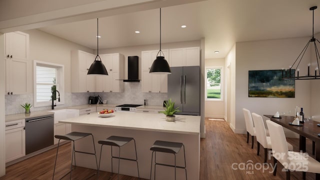 kitchen with a center island, a breakfast bar, appliances with stainless steel finishes, white cabinets, and wall chimney range hood