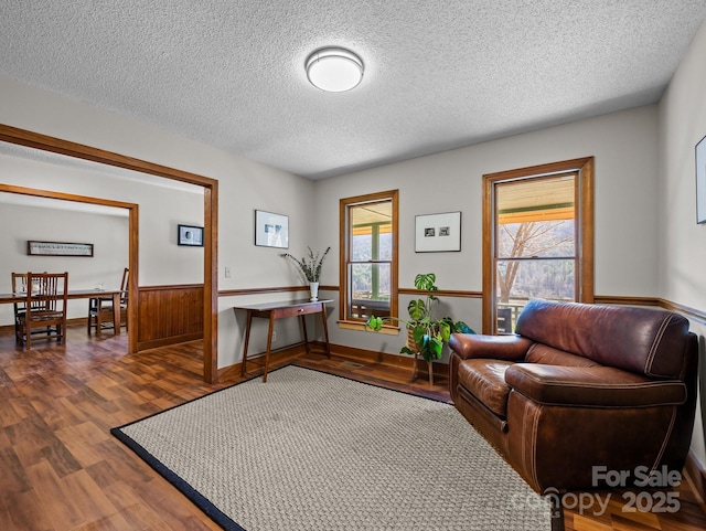 sitting room featuring plenty of natural light, wainscoting, a textured ceiling, and wood finished floors