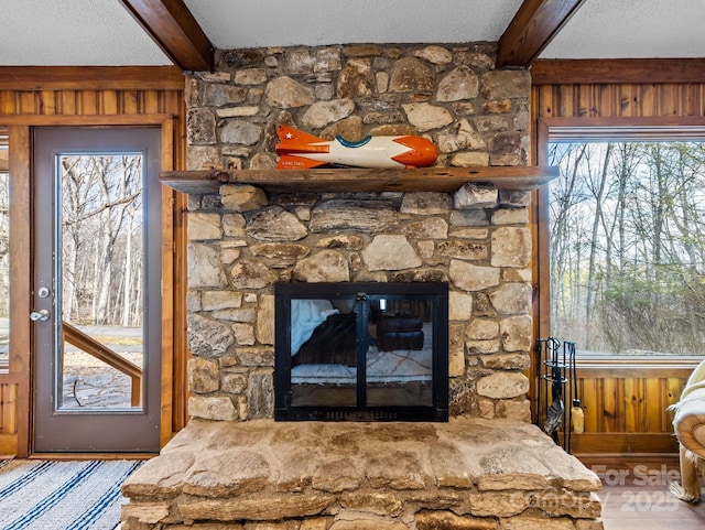 details with beamed ceiling, a fireplace, wood walls, and a textured ceiling