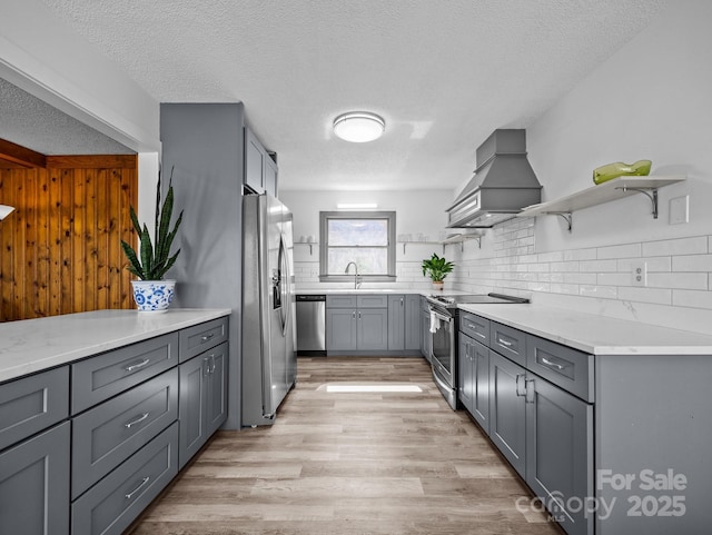 kitchen with open shelves, gray cabinetry, premium range hood, and stainless steel appliances