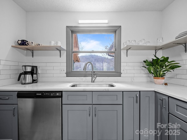 kitchen with stainless steel dishwasher, open shelves, gray cabinetry, and a sink