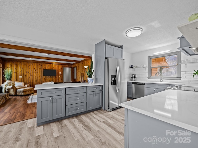 kitchen with light countertops, gray cabinets, appliances with stainless steel finishes, light wood-style floors, and open shelves