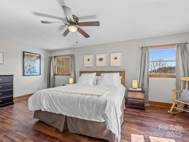 bedroom with dark wood finished floors, multiple windows, a textured ceiling, and baseboards