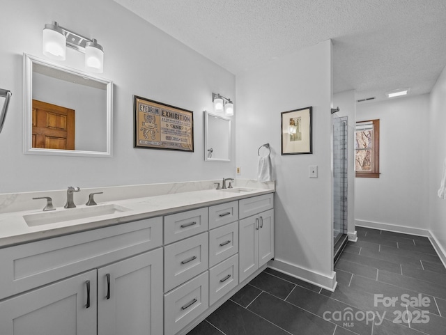 bathroom featuring a sink, a shower with door, a textured ceiling, tile patterned flooring, and double vanity