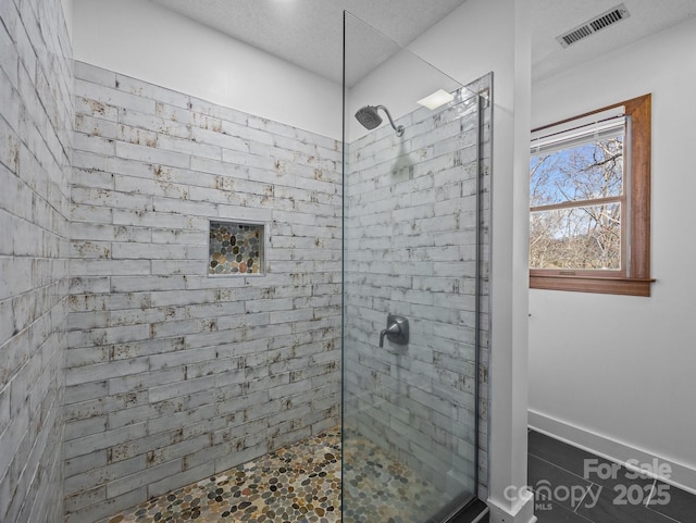 full bathroom featuring a tile shower and visible vents