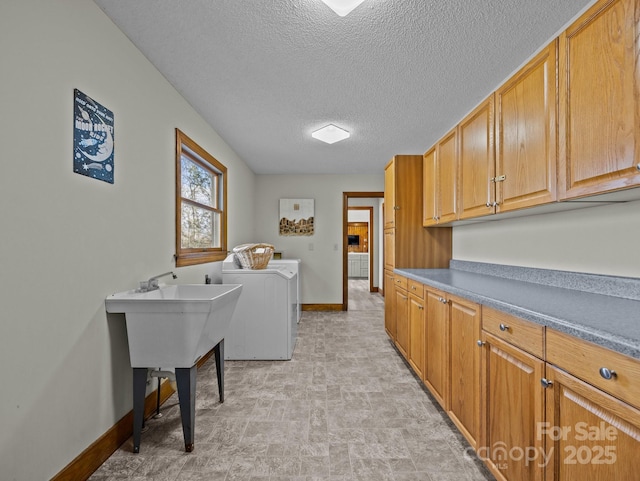 laundry room featuring baseboards, cabinet space, a textured ceiling, and washer and clothes dryer