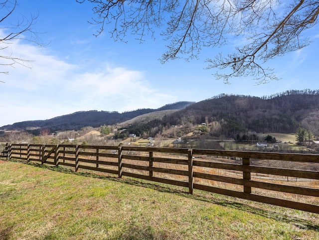 view of yard with a rural view, fence, and a mountain view