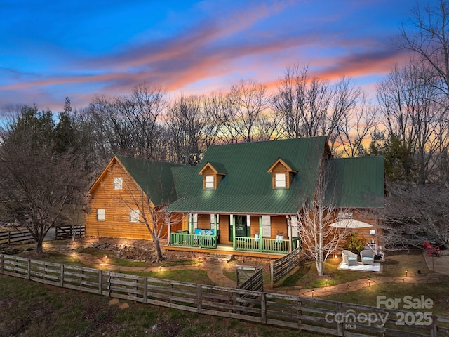 view of front of property with covered porch, a fenced front yard, and metal roof