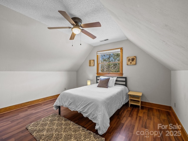 bedroom featuring visible vents, a textured ceiling, baseboards, and wood finished floors