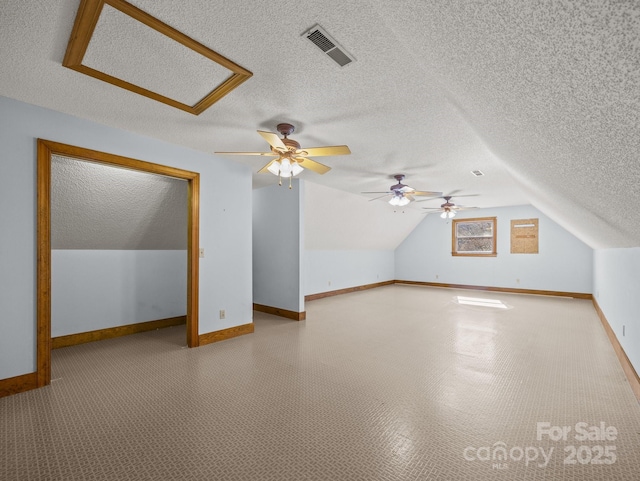 bonus room featuring visible vents, a textured ceiling, baseboards, attic access, and vaulted ceiling