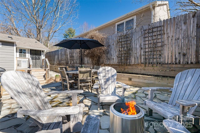 view of patio with a fire pit, outdoor dining space, and fence