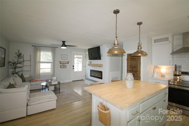 kitchen with a glass covered fireplace, open floor plan, white cabinetry, and electric range