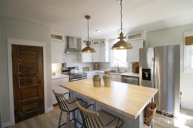 kitchen with a center island, stainless steel appliances, wooden counters, decorative backsplash, and wall chimney exhaust hood