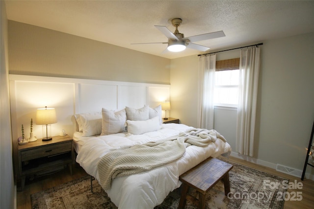 bedroom featuring a textured ceiling, wood finished floors, and a ceiling fan