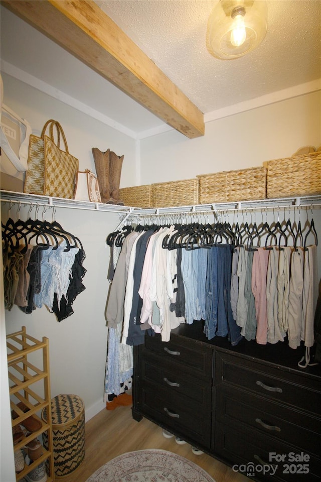 spacious closet with light wood finished floors and beamed ceiling