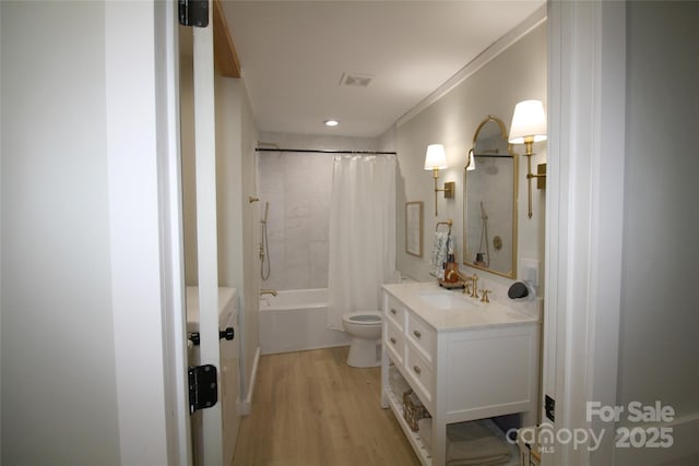 bathroom featuring visible vents, shower / bathtub combination with curtain, toilet, vanity, and wood finished floors