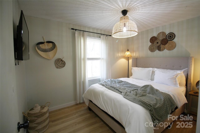 bedroom with baseboards and wood finished floors