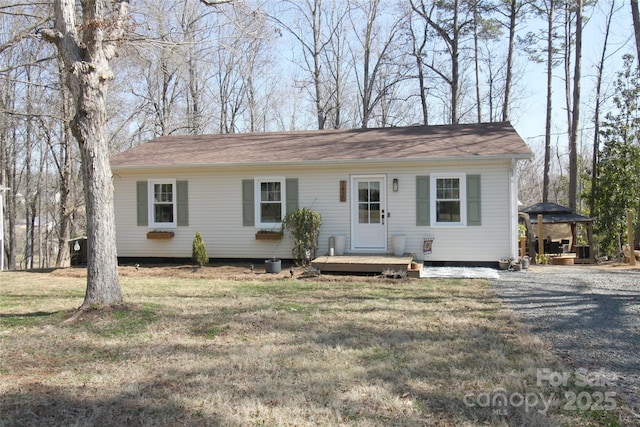 view of front of property featuring gravel driveway, a deck, and a front yard