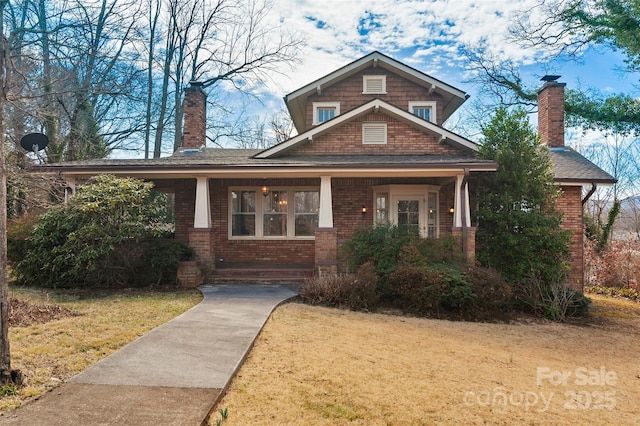 craftsman-style home featuring brick siding, a chimney, and a front yard