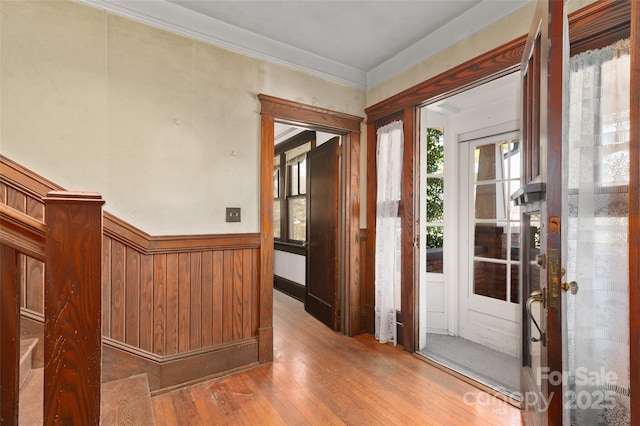 foyer entrance with wood-type flooring, wainscoting, and crown molding