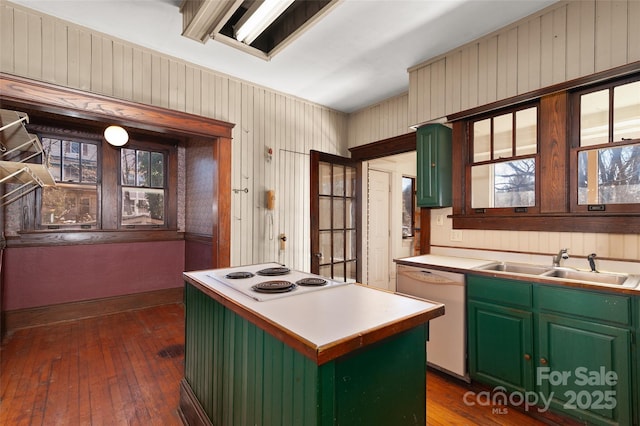 kitchen featuring cooktop, green cabinetry, white dishwasher, and a sink