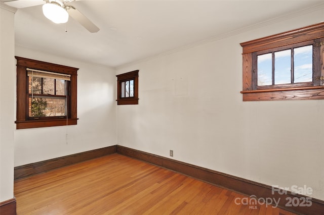 empty room featuring baseboards, crown molding, light wood-style flooring, and a healthy amount of sunlight