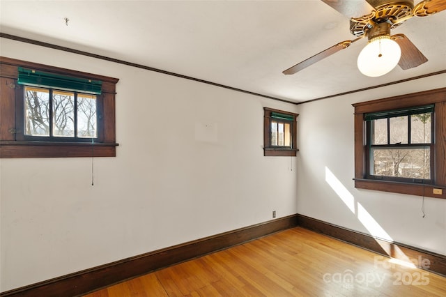 empty room featuring light wood finished floors, baseboards, and ornamental molding